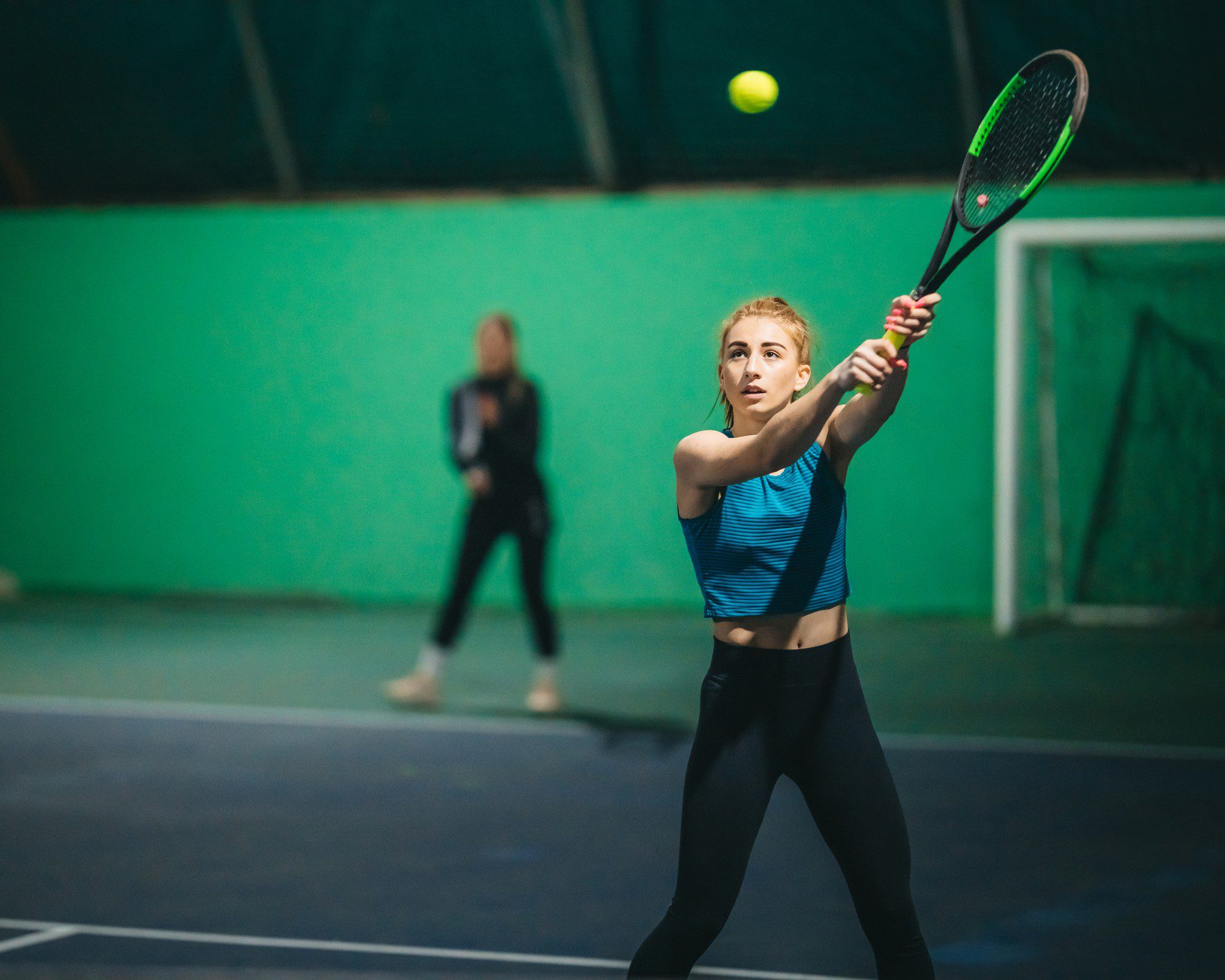 Woman playing tennis on indoor court.