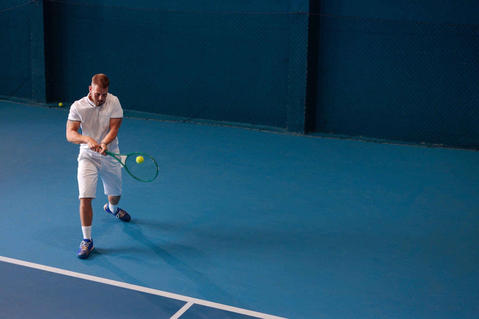 Man playing tennis on blue court.