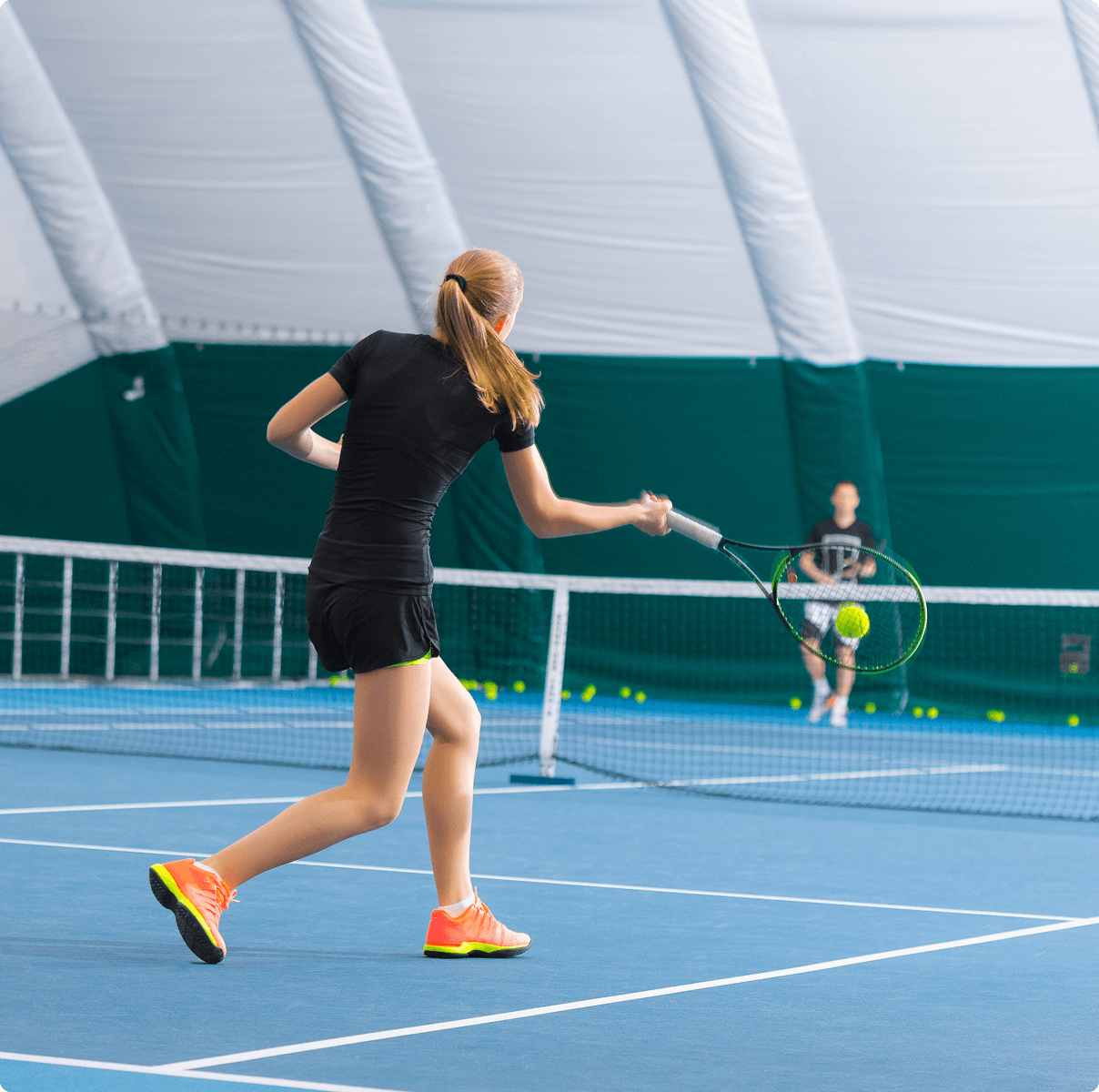 Woman playing tennis on indoor court.
